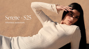 Ein Model liegt in einem gerippten, cremefarbenen "Almond White Pointelle Beach Dress" auf einem sandigen Hintergrund am Strand in einer warmen und sonnigen Umgebung. Das Banner enthält auch den Text "Serene - S25" und "Effortless essentials".
